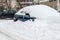 Car covered with snow in the street yard