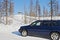 Car crosses the line of northern polar circle along winter road near the sign `Polar Circle`