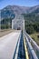 Car crosses a transport metal bridge with limited clearance over the Columbia River amid majestic forested mountains