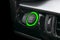 Car dashboard with focus on green engine start stop button. Car interior details. Car detailing.