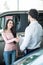 Car dealer handshaking with happy female in automobile center