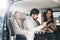 Car Dealership. The Asian Salesman woman checking the list with the middle east customer inside the new car with plastic wrapped