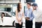 Car Dealership. The Asian Salesman woman and man checking the list with the middle east customer before hand over.