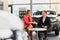 Car dealership sales person at work concept. Portrait of young sales representative wearing formal wear suit, showing vehicles at