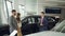Car dealership worker is talking to beautiful couple bearded man and his attractive wife while standing near luxury car