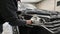 Car detailing - the man washes headlights of a car with a hand covered with a special wash glove, close-up.