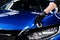 Car detailing studio or car wash worker applying ceramic car coating on blue car