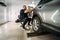 Car detailing. Worker prepares rear lights of SUV for polishing in garage