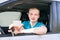 Car driver. Caucasian teen boy showing driver license, new car k