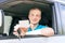 Car driver. Caucasian teen boy showing an empty white card, car