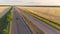 The car drives along the colorful highway between the wheat fields at sunset, the car rides along the road between two