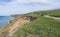 The car drives along a dirt road along the seashore.