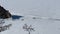 The car drives along the frozen Lake Baikal, not far from Shamanka Mountain.