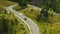 Car drives on curvy road built in highland with fir trees