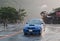 Car drives fast on city road at rainfall.