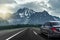 The car drives fast on the highway against the backdrop of a mountain range.