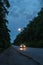 The car drives late on the road. The moon over the road