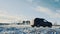 A car drives on a snow-covered road in the countryside