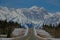 Car driving along the empty road offering a view of the snowy Canadian Rockies