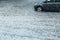 Car driving through big water puddle on street during heavy rain