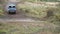 A car is driving in the countryside participating in the race and crossing wide dirty puddle, making giant water splash