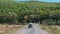 Car Driving Down Road Next to Lush Green Hillside