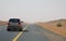 Car driving on an empty road in the deserts of Dubai, UAE