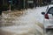 Car driving on flooded road with Flood water flow through the road after heavy winds and storm surges