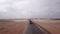 Car driving on gravel road in aerial desert. Sandy landscape, nobody in Namibia.