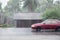 Car driving motion through gale rain on front wooden house