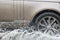 Car driving through a puddle on a flooded road with water and splashes caused by heavy rain.