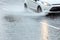 Car driving through puddles on flooded street