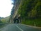 Car driving on road into tunnel carved out rock of mountain