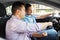 Car driving school instructor teaching male driver