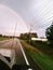 Car driving towards a rainbow.