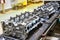 Car engine cylinder heads in housings on conveyor in shop