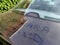 Car in Europe covered in Sahara sand transported by southerly winds, words written in dust