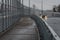 A car with a faulty left-hand headlight travels along the expressway. High shield anti-noise protective fences along the road.