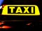 Car with glowing taxi sign moving in the night