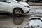 The car goes without reducing speed on a bad road with asphalt in pits and potholes, hitting the wheel in a puddle, spraying melt