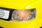 Car headlight of yellow automobile closeup