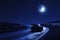 A car with headlights on drives down a dimly lit road during the nighttime, A sports car under moonlight on a winding road, AI