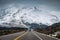 Car on highway and snowy mountain range in gloomy at Icefields Parkway