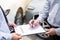 Car insurance agent send a pen to his customers sign the insurance form on clipboard while examining car after accident claim