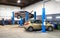 Car on lift in mechanic shop or garage, interior of auto repair workshop, vehicles inside maintenance