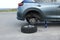 Car lifted by scissor jack and new wheel on roadside outdoors. Tire puncture