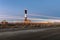 Car lights streaking by a lighthouse has they drive down a dirt road. Fire Island, NY