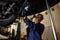 Car maintenance and warranty repair in a repair shop. A technician uses flashlight lamp checking the chassis for wheel alignment