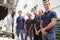 Car mechanic and apprentices in a garage looking to camera