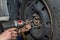 The car mechanic bolts the steel car wheel with a pneumatic wrench in a car workshop, visible male hands.